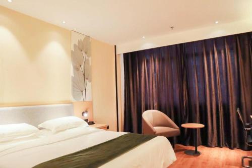 a hotel room with a bed and a chair at GreenTree Inn Yichun Mingyueshan Airport in Yichun