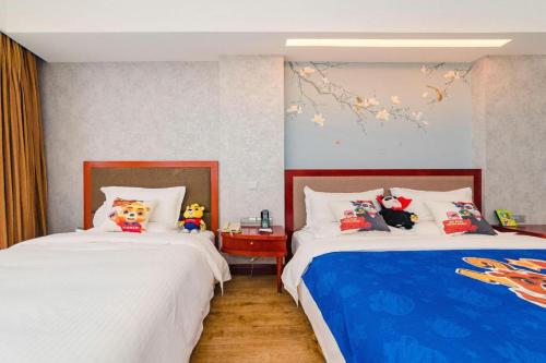 a bedroom with two beds with stuffed animals on them at Junyu Grand Hotel Qinhuangdao in Qinhuangdao