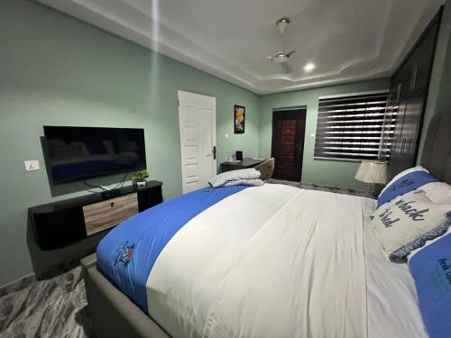 a bedroom with a large bed and a flat screen tv at Arek Condos Accra in Sotuom