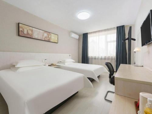 a hotel room with two beds and a window at Jinjiang Inn Dalian Development Zone Jinma Road Light Railway Station in Jinzhou