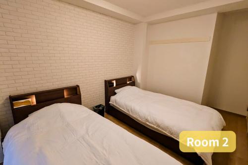 a room with two beds and a brick wall at Vacation House 2 in Funabashi