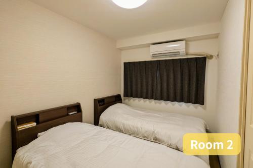 a room with two beds and a window with a heater at Vacation House 2 in Funabashi