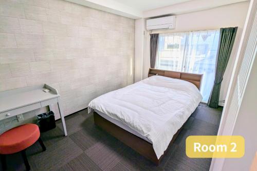 a bedroom with a bed and a desk and a window at Vacation House 2 in Funabashi
