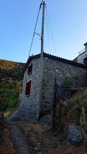 a stone building with red windows on a hill at Menelia in Sykaminéa