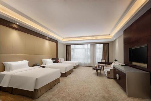 a hotel room with three beds and a flat screen tv at Linyi Blue Horizon International Hotel Yi He in Linyi