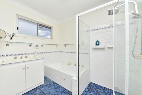 a white bathroom with a tub and a glass shower at Andres Farm Cottage in Broke