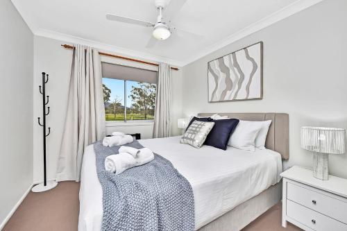a white bedroom with a bed and a window at Andres Farm Cottage in Broke