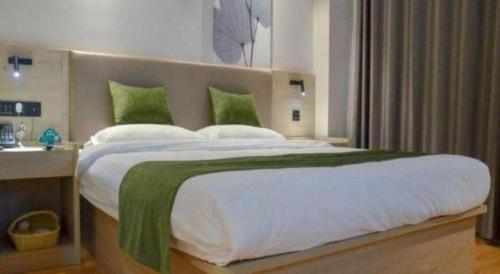 a bedroom with a large bed with green pillows at GreenTree Inn Xuzhou High Speed Railway Station Express Hotel in Xuzhou