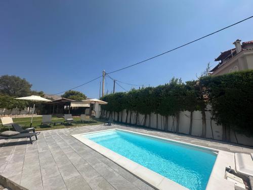 a swimming pool in front of a house at Lagonisi Luxury Escape in Lagonissi