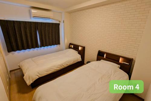 two beds in a room with a brick wall at Vacation House 2 in Funabashi