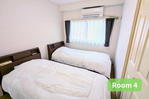 two beds in a small room with a window at Vacation House 2 in Funabashi