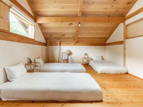 two beds in a room with wooden ceilings at Kitaarupusu ichibō no ie - Vacation STAY 96488v in Omachi