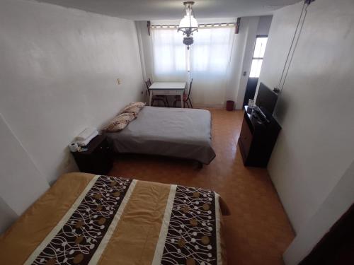 a room with two beds and a table and a desk at Hotelito Ejido de la 10 in Puebla