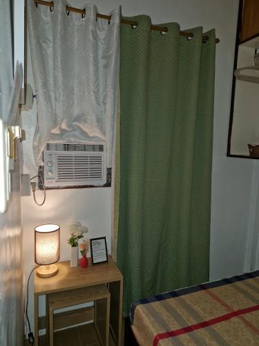 a bedroom with a green curtain and a air conditioner at AJ Transient House in Gairan