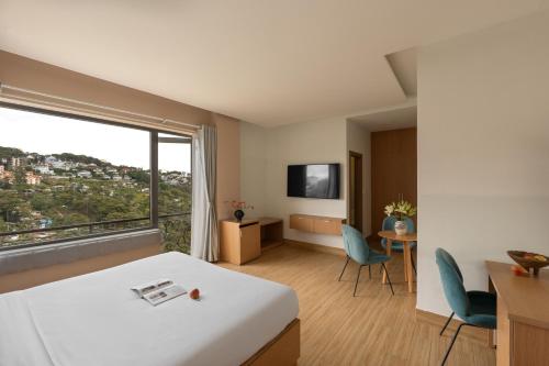 a hotel room with a bed and a table and chairs at Gold View Boutique Hotel Đà Lạt in Da Lat