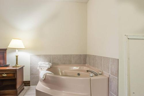 een badkamer met een bad, een tafel en een lamp bij Rodeway Inn Brookville in Brookville