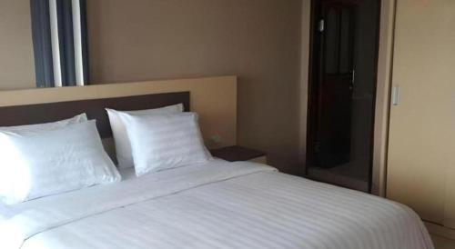 a bed with white sheets and pillows in a room at Samosir Cottages Resort in Tuk Tuk