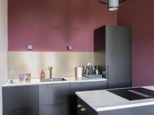 a kitchen with pink and grey cabinets and a sink at Kiel Windeweer - Eindeloos uitzicht in Kiel