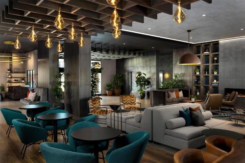 a lobby with a couch and tables and chairs at Hotel Avail Rogers, Tapestry Collection By Hilton in Rogers
