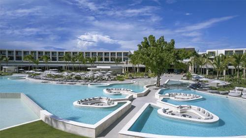 a resort with several pools and chairs and a building at Zemi Miches Punta Cana All-Inclusive Resort, Curio by Hilton in Miches