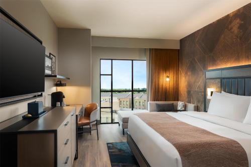 a hotel room with a bed and a flat screen tv at Hotel Avail Rogers, Tapestry Collection By Hilton in Rogers