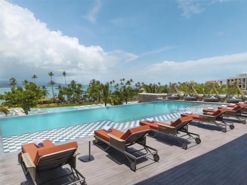 a pool at a resort with lounge chairs and the ocean at Zemi Miches Punta Cana All-Inclusive Resort, Curio by Hilton in Miches