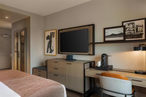a bedroom with a bed and a desk with a television at Hotel Avail Rogers, Tapestry Collection By Hilton in Rogers
