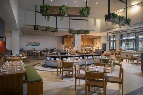 a restaurant with tables and chairs and a bar at Zemi Miches Punta Cana All-Inclusive Resort, Curio by Hilton in Miches