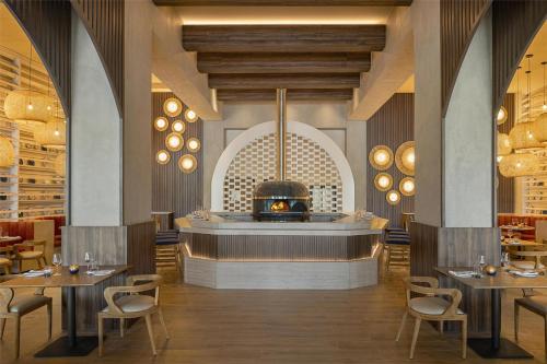 a restaurant with a fireplace and tables and chairs at Zemi Miches Punta Cana All-Inclusive Resort, Curio by Hilton in Miches