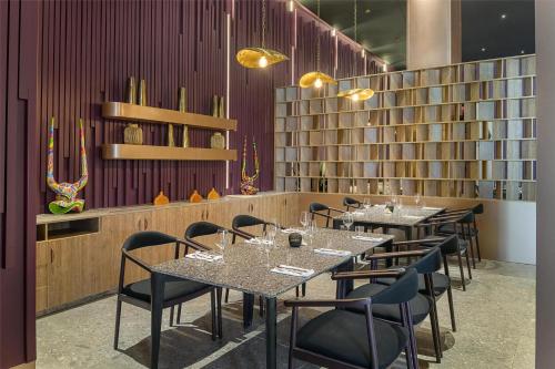 a dining room with tables and chairs and books at Zemi Miches Punta Cana All-Inclusive Resort, Curio by Hilton in Miches