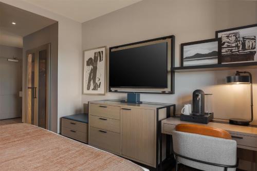 a bedroom with a television and a desk with a chair at Hotel Avail Rogers, Tapestry Collection By Hilton in Rogers