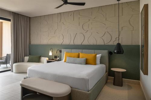 a bedroom with a large bed with yellow pillows at Zemi Miches Punta Cana All-Inclusive Resort, Curio by Hilton in Miches