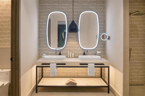 a bathroom with two sinks and two mirrors at Zemi Miches Punta Cana All-Inclusive Resort, Curio by Hilton in Miches