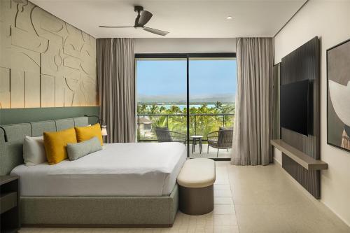 a hotel room with a bed and a balcony at Zemi Miches Punta Cana All-Inclusive Resort, Curio by Hilton in Miches