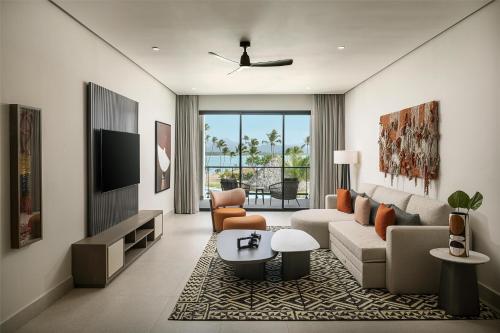 a living room with a couch and a tv at Zemi Miches Punta Cana All-Inclusive Resort, Curio by Hilton in Miches