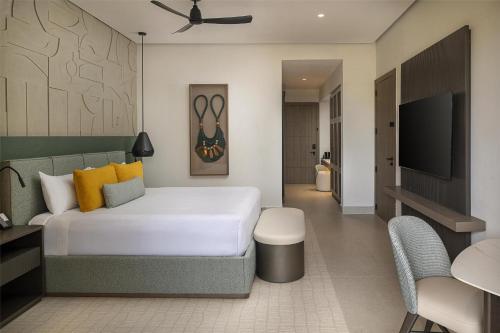 a bedroom with a bed and a flat screen tv at Zemi Miches Punta Cana All-Inclusive Resort, Curio by Hilton in Miches
