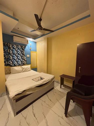 1 dormitorio con 1 cama con ventilador de techo y silla en Hotel Sunset Park, en Calcuta