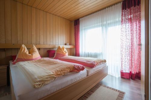a bedroom with a bed and a window with red curtains at Hotel Haus Gertrud in Simmerath