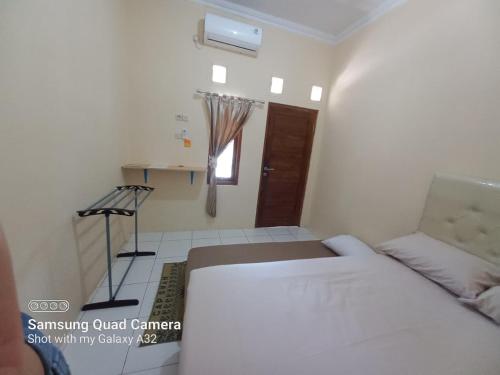 a white bedroom with a bed and a window at Niti Guest House in Tegalan