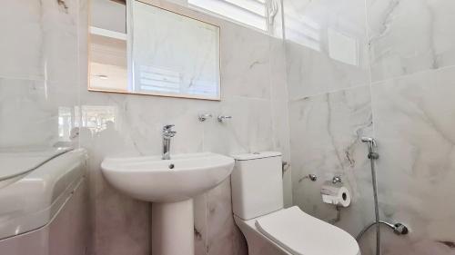 a white bathroom with a toilet and a sink at Maison Lakazbleu - 100m plage Mont Choisy in Mont Choisy