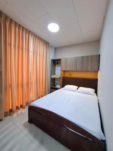 1 dormitorio con 1 cama grande y cortinas de color naranja en Ikitu House, en Iquitos
