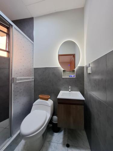 Un baño con inodoro, lavabo y espejo. en Ikitu House, en Iquitos