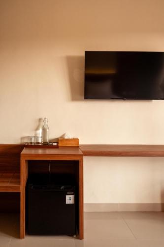 a room with a table with a television on a wall at Puri Kaja House in Badung