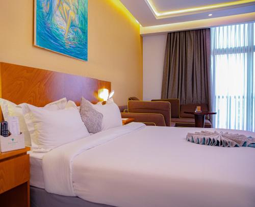 a hotel room with a large white bed and chairs at Azzeman Hotel in Addis Ababa