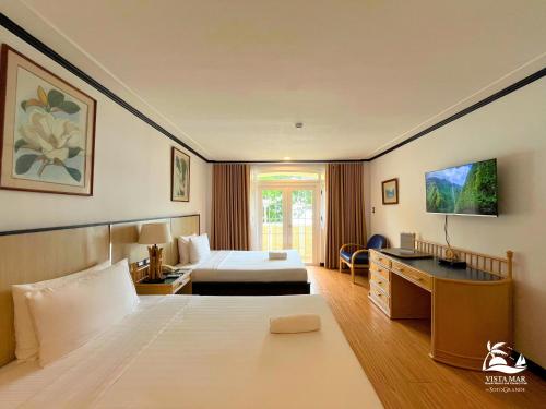 a hotel room with a bed and a desk at Vista Mar Beach Resort and Country Club in Mactan
