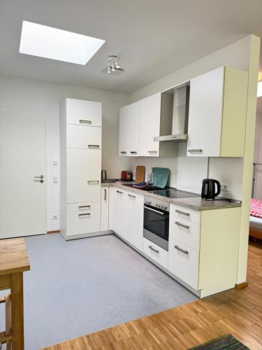 a white kitchen with white cabinets and a table at K9 Wohnungen in Münster