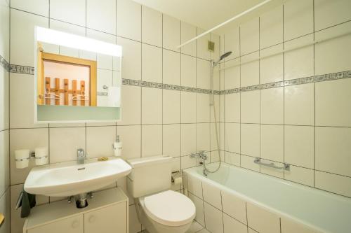 a white bathroom with a toilet and a sink at Edelweiss Ferienwohnung, Attica Muntognas in Flims