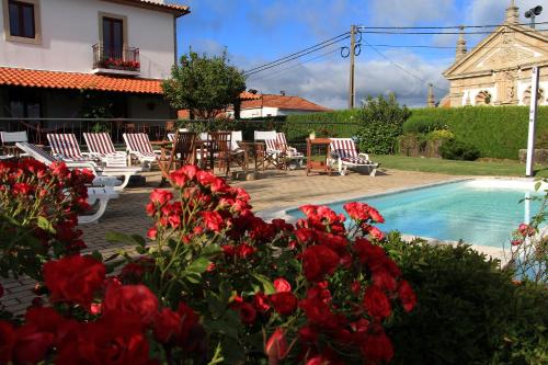 a house with a swimming pool and red flowers at Casa Paz do Outeiro in Paredes de Coura