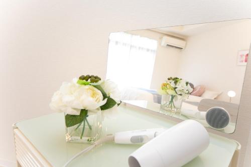 a vase of flowers on a table in front of a mirror at Miraie Kuwana Shimofukayabe 2 in Kuwana