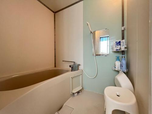 a bathroom with a tub and a toilet and a sink at あさひシーサイドコテージ in Asahi